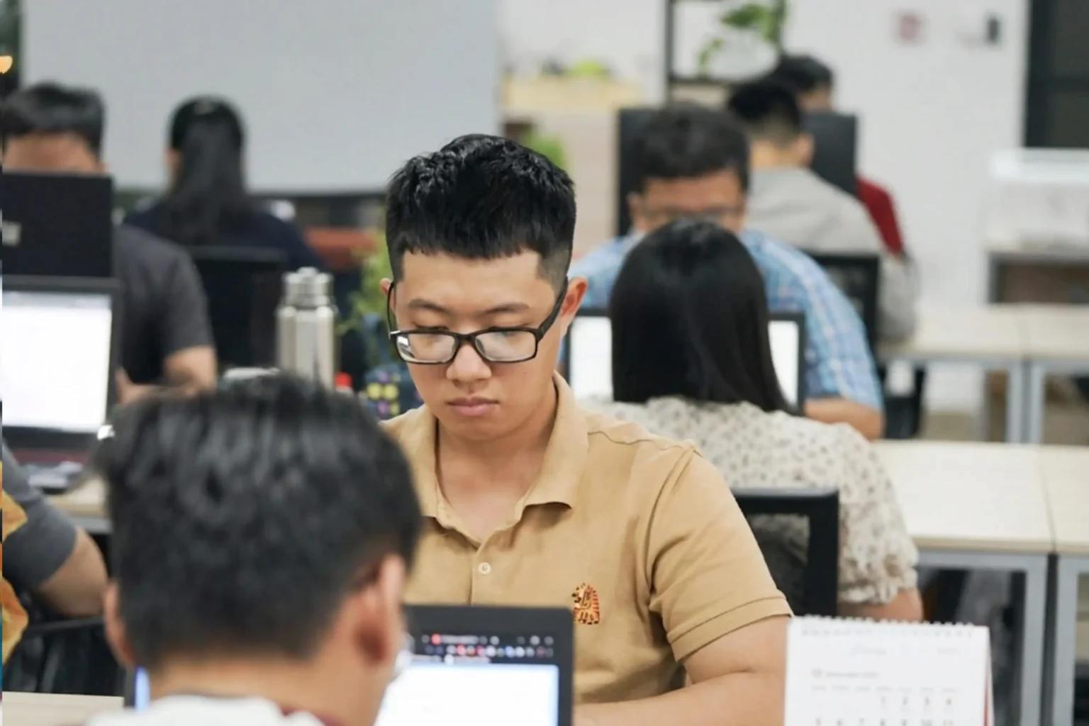 An InApps engineer at a desk in the Ho Chi Minh City office, colleagues working at desks behind