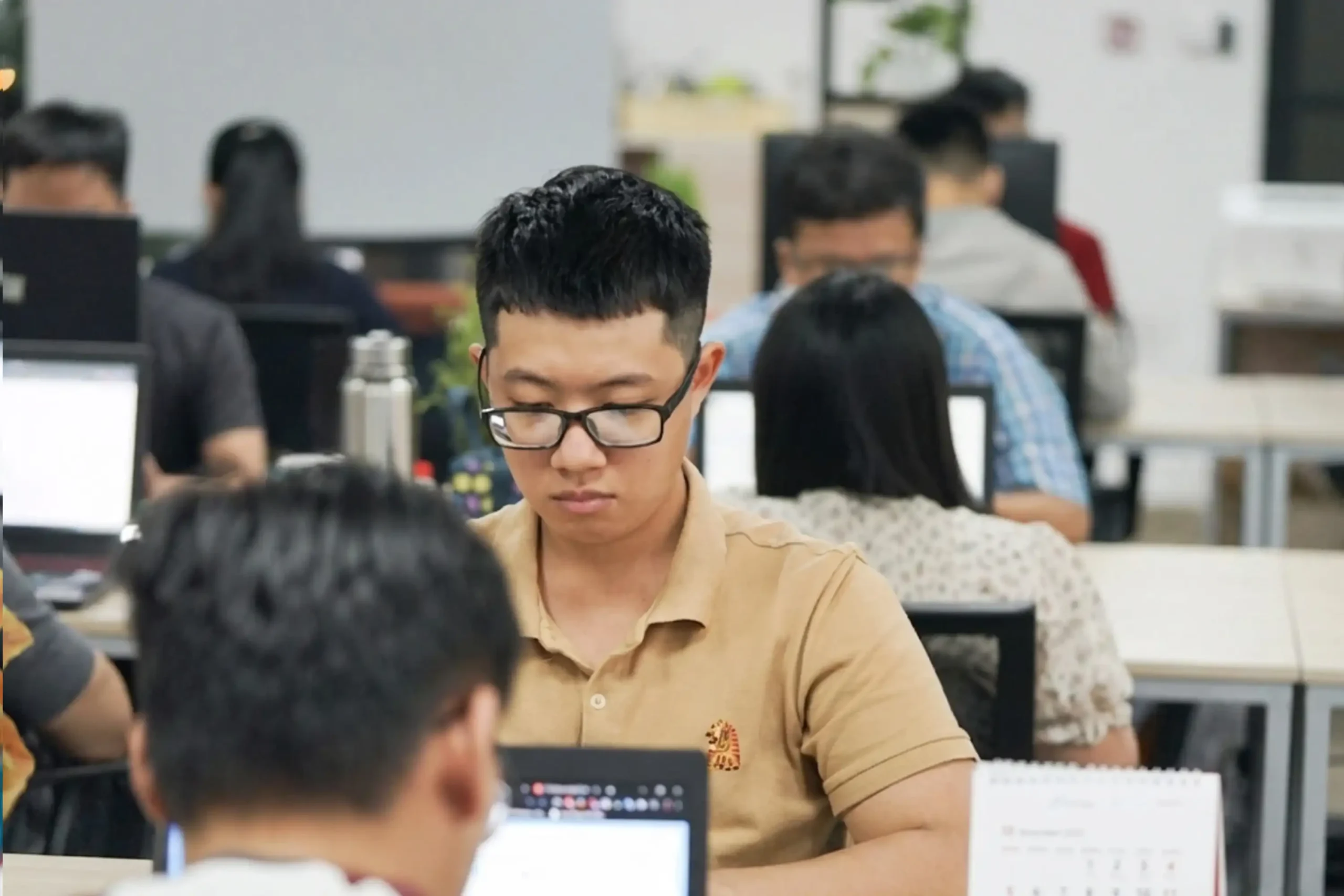 An InApps developer working at a laptop, with the engineering team at their desks in the open-plan Ho Chi Minh City office
